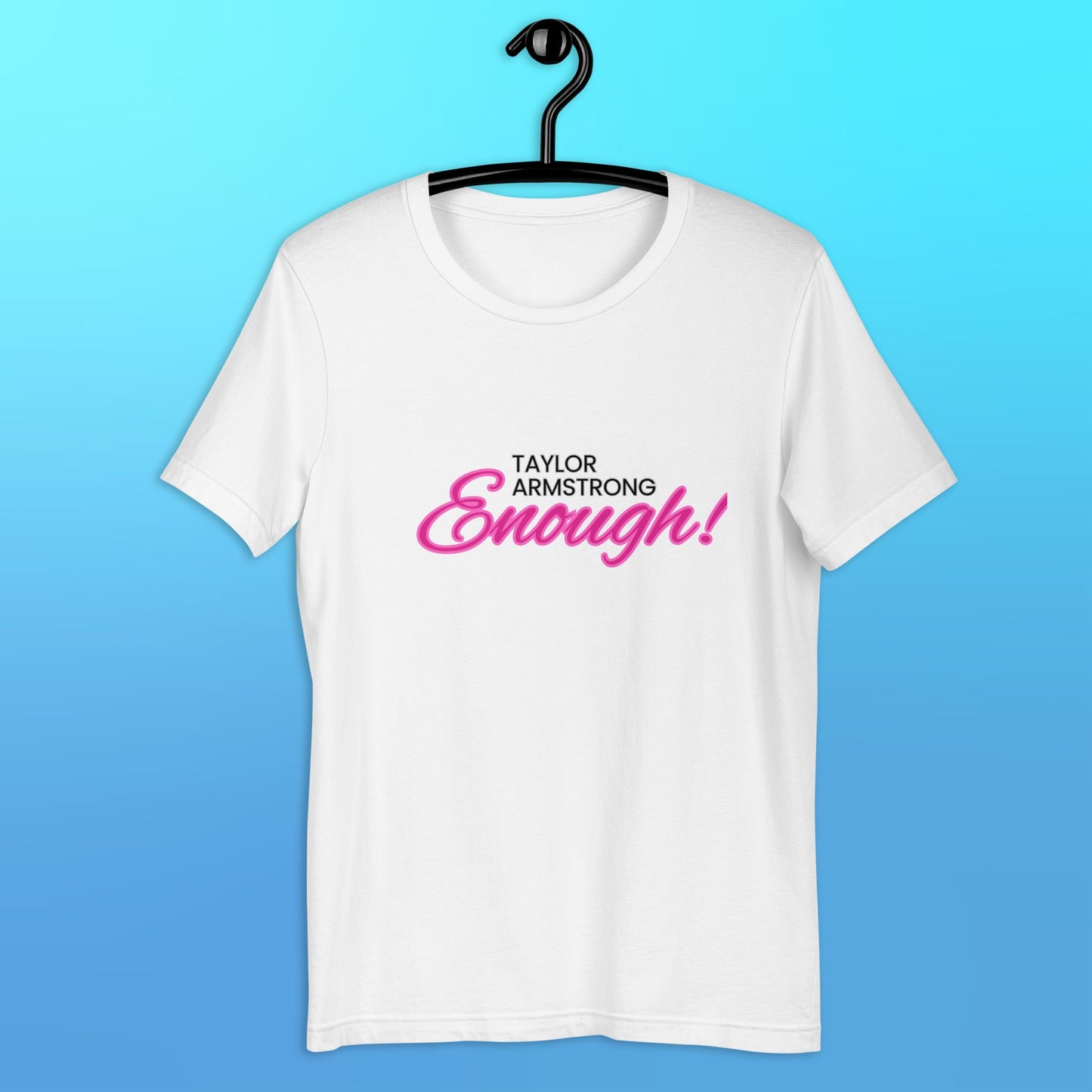 A white t-shirt that reads "Taylor Armstrong ENOUGH!" in black and pink lettering hanging on a black hanger..