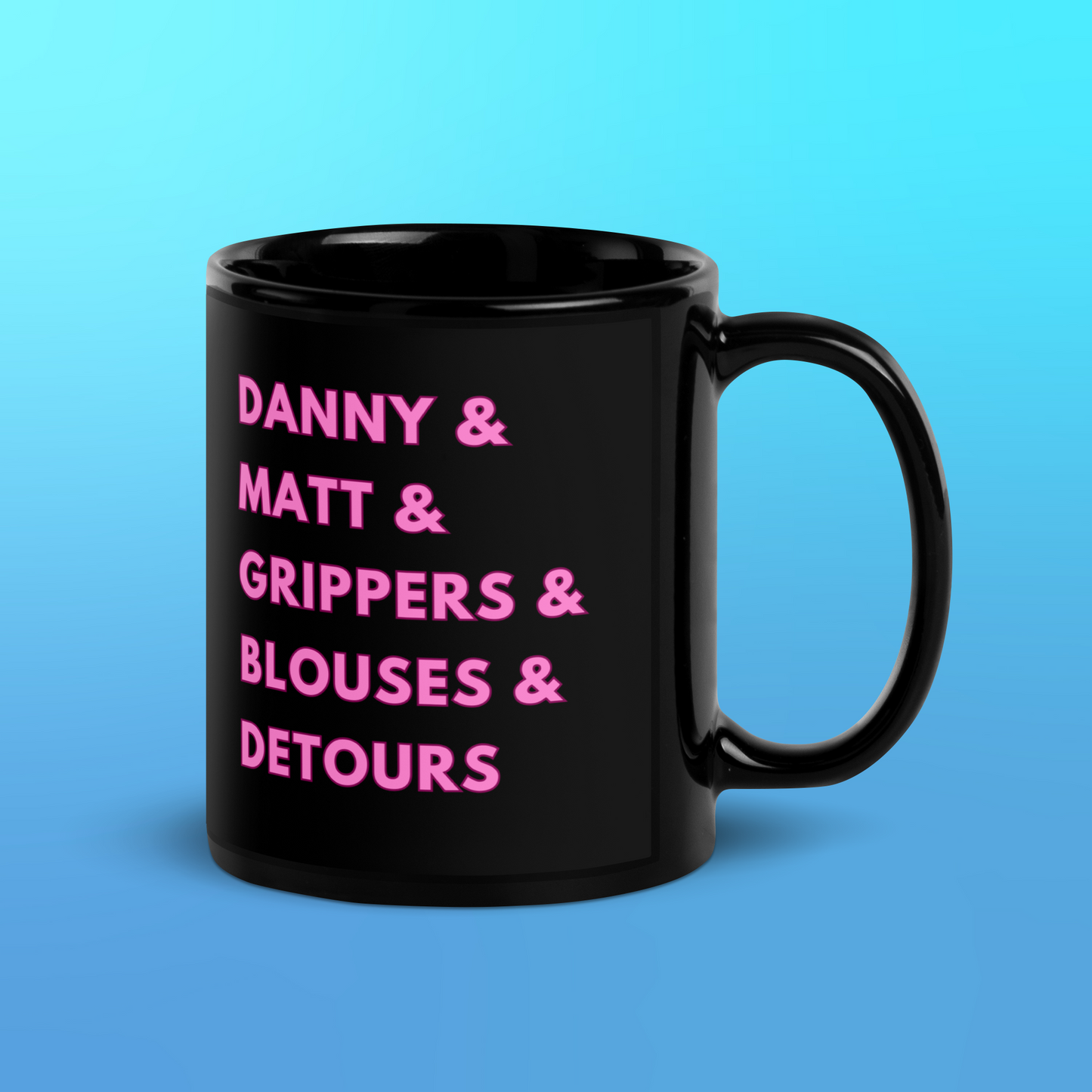 A glossy black mug on a blue background that reads "Danny & Matt & Grippers & Blouses & Detours" in pink uppercase font with a darker pink border.