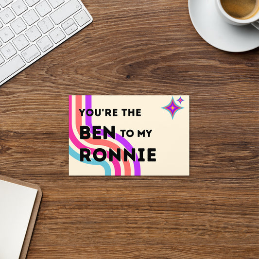 The front of a greeting card that says "You're the Ben to my Ronnie" in black font on top of colorful (blue, pink, orange and purple) curved stripes with two coordinating atomic stars in the upper right corner.